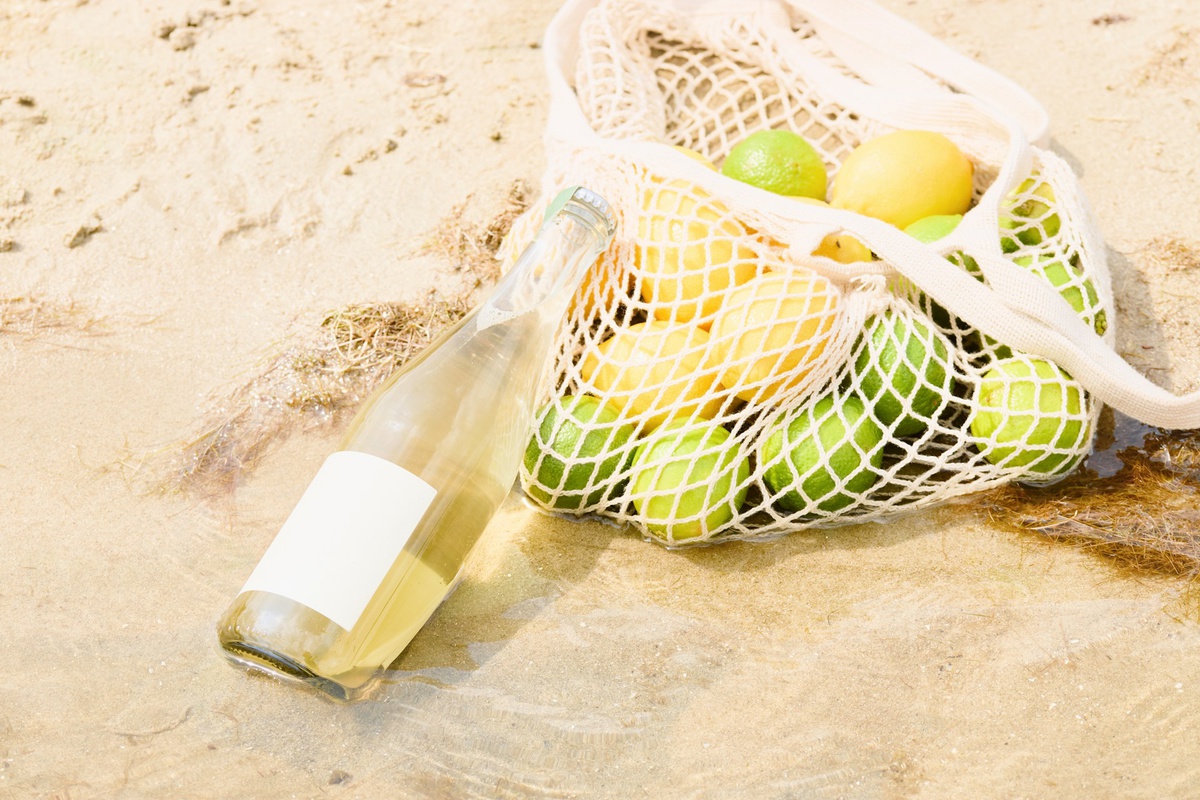 Butelka lemoniady na siatce z limonkami i cytrynami